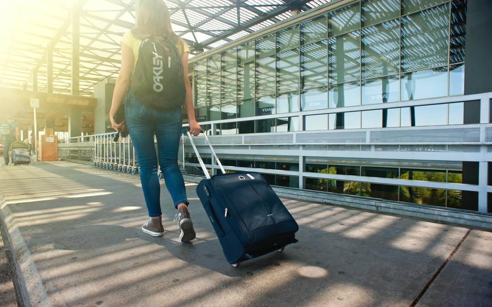 a woman pulls a trolley along the sidewalk on her way to vancouver at abbotsford international airport
