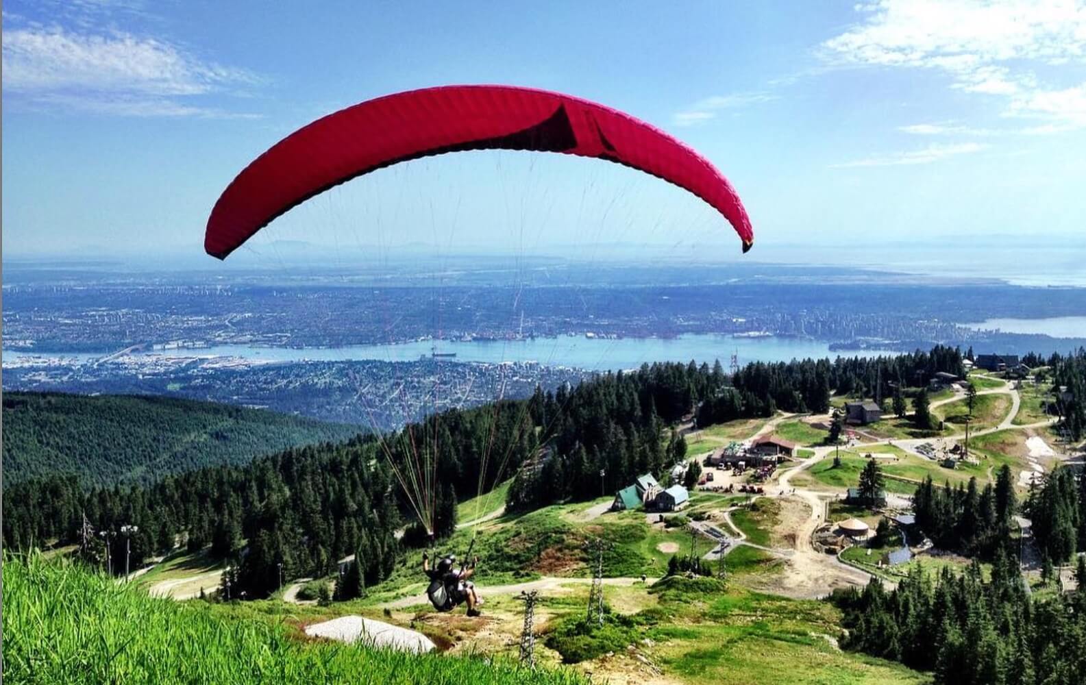 A man paraglides off the peak of Grouse Mountain