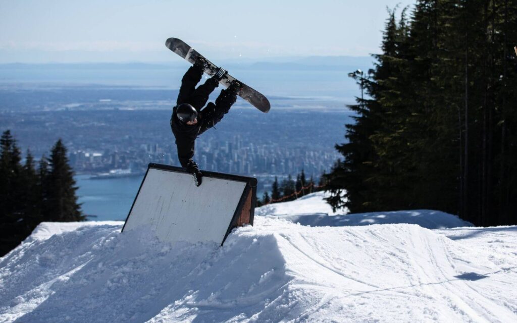 a snowboarder taking a jump at the terrain park at grouse mountain in vancouver bc
