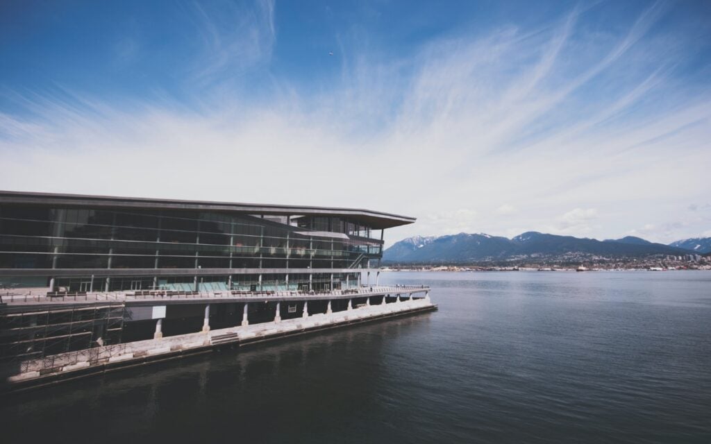 view of vancouver convention center building facing the vast clear sea with a backdrop of the mountain at coal harbour where do cruise ships dock in vancouver