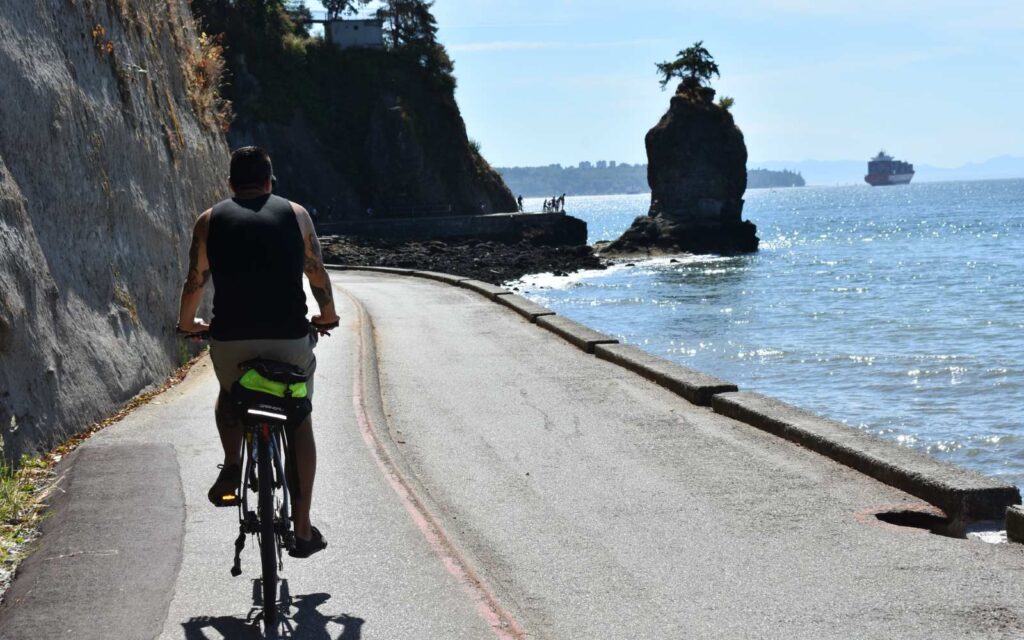 cyclist riding the vancouver seawall with siwash rock in the background