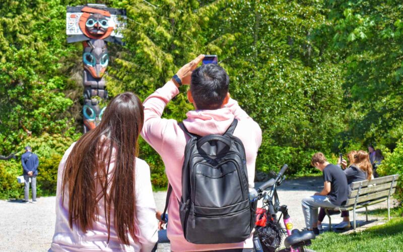 people taking pictures of the totem poles in stanley park vancouver bc