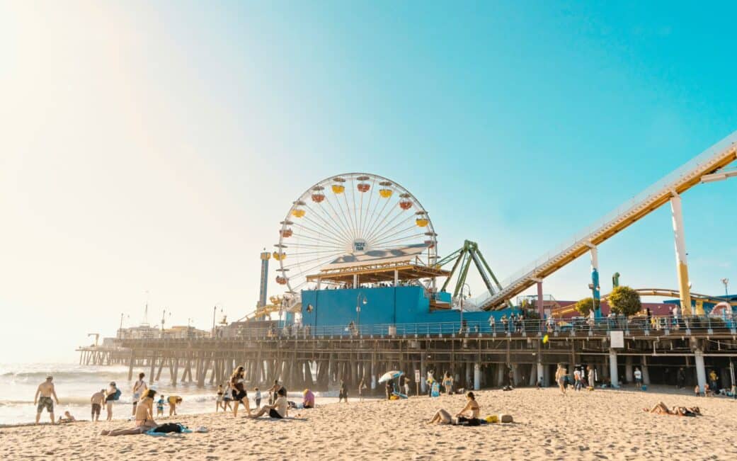 People lounge on the beach in front of Santa Monica Pier.