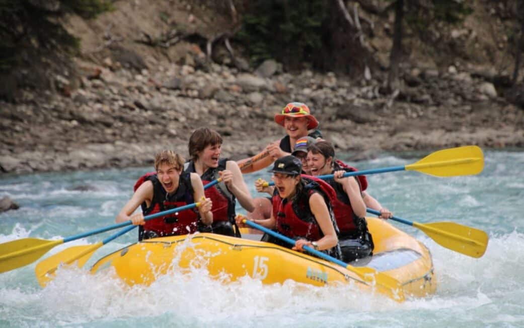 A group enjoys the rapids while white water rafting on a road trip from Vancouver to Jasper.