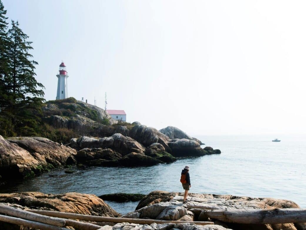 the lighthouse at lighthouse park with a man standing on the rock formations forming right along the sea one of the things to do in west vancouver