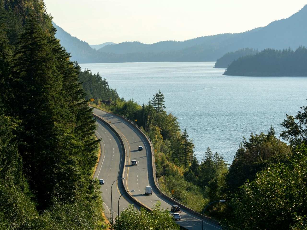 sea to sky highway in vancouver bc surrounded by trees, mountains and a breathtaking view of the ocean