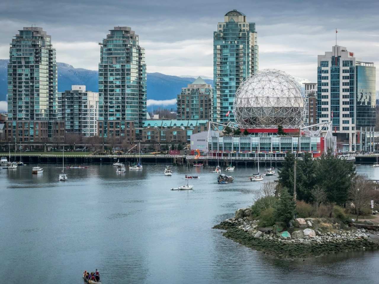 a cloudy day by the vancouver harbor showing its buildings at the back