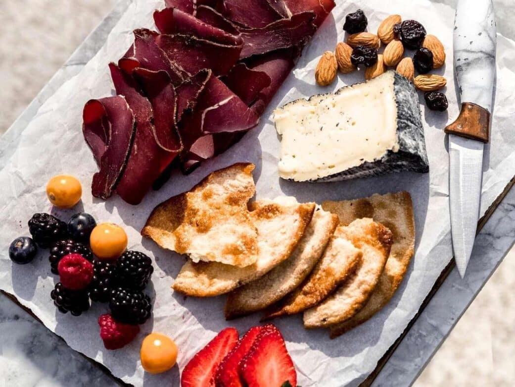 a charcuterie board sampler with berries, meat, cheese, crackers and nuts at oyama sausage co