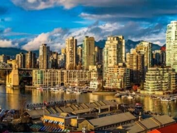 sunlight strikes the high-rises around granville island as boats bob below in false creek—classic vancouver mix of market energy, urban skyline, and waterfront calm